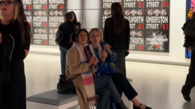 Two people sit on a bench in the middle of an exhibition