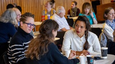 Three women in conversation aroud a table, each making notes