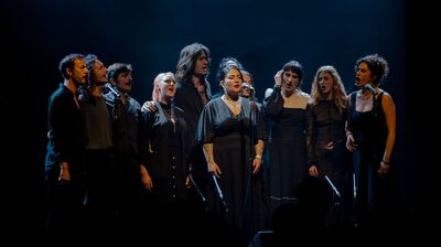Idrîsî Ensemble singers performing dressed in black on a dark stage