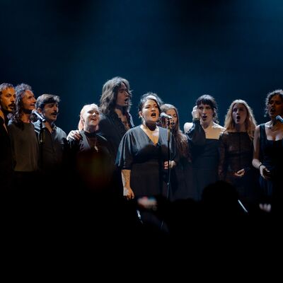 Mixed choir singers performing dressed in black on a dark stage