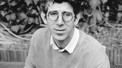 A black and white portrait of a man wearing round glasses