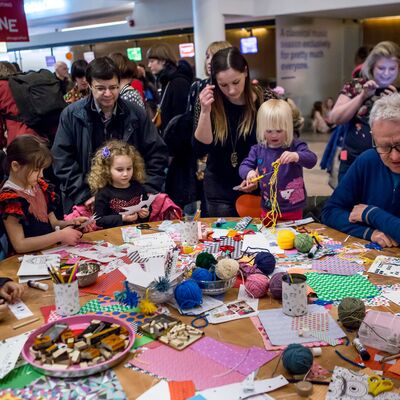 A group of children and parents doing arts and crafts around a wooden table