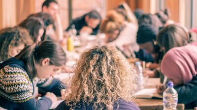 Group of people sitting around a table at a workshop writing and chatting