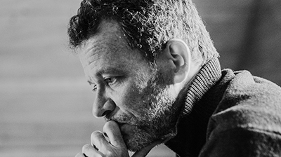 Black and white photo of Yann Martel with his head in his fist.