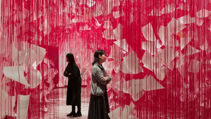 Two people stand on either side of an open door in Chiharu Shiota: Threads of Life