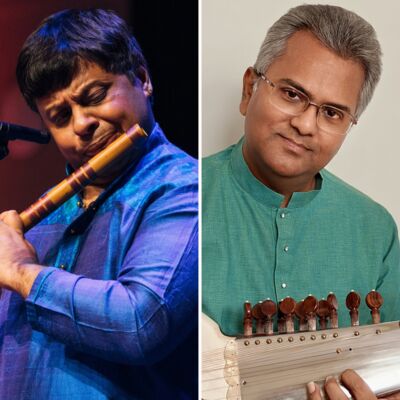 Two musicians, on the left wearing blue and playing a wooden flute and on the right wearing green holding a sitar