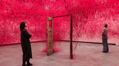 Two people stand on either side of an open door in Chiharu Shiota: Threads of Life