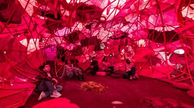 A group of people in a red installation made of second hand clothing