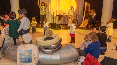 Young families watching performers with a harp and a piano
