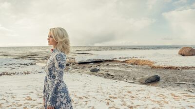 Organist iveta apkalna in floral dress on a snow covered beach in Latvia