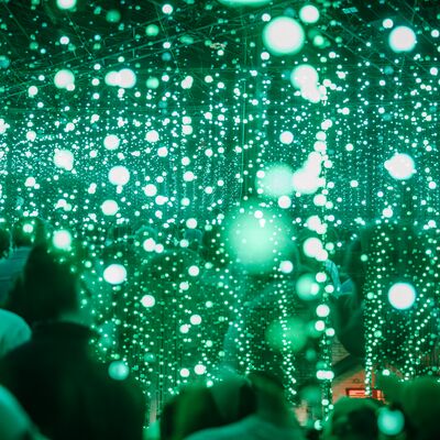Green droplets of light hang in rows and rows from the ceiling, people stand beneath them