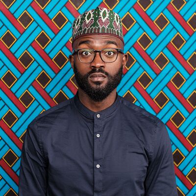 A profile photograph of a man with a beard wearing a colourful kufi hat