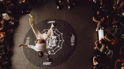 A performer does a trick surrounded by an audience