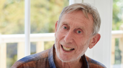 A man smiling wearing a plaid shirt