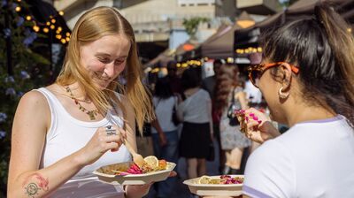 Two people hold plates and eat in the Food Market