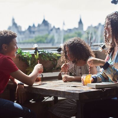 a woman and two children smiling and drinking from straws in the sun
