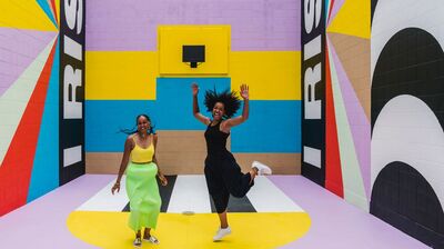 Two people smiling in a large colourful room
