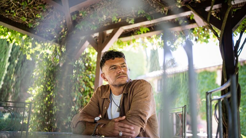 Poet Raymond Antronbus sits at a table in the covered area of a garden