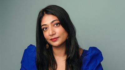 Nussaibah Younis wearing a blue dress sitting at a blue table.