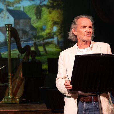 Anton Lesser standing at a lectern onstage.