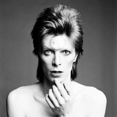 A black and white image of David Bowie, staring directly into the camera with a spiky mullet.