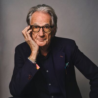 Paul Smith sitting with his head in his hand against a grey background.