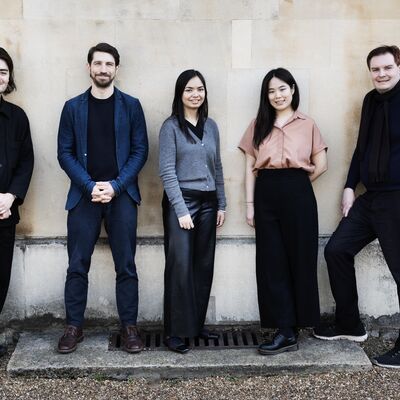 Five LPO Young Composers standing in front of a beige wall.