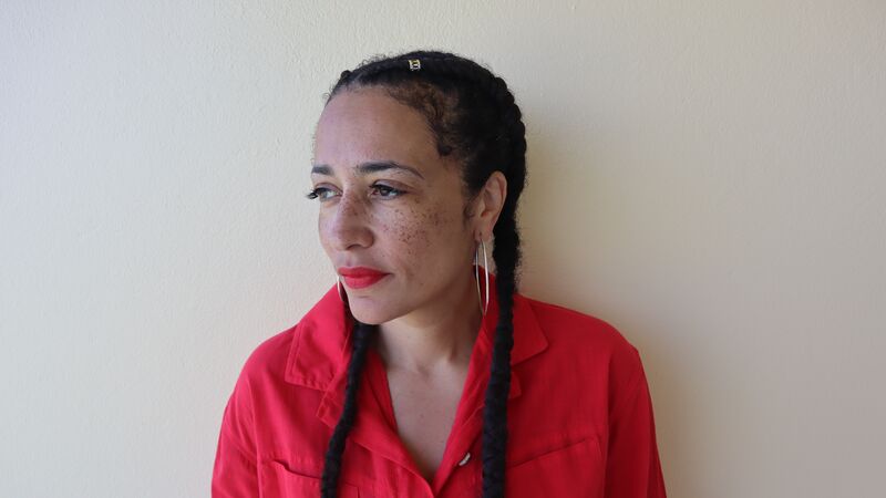 Author Zadie Smith wearing hoop earrings and a red shirt
