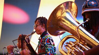 Three young jazz musicians playing the tuba, saxophone and singing perform on stage as part of Tomorrow's Warriors ensemble