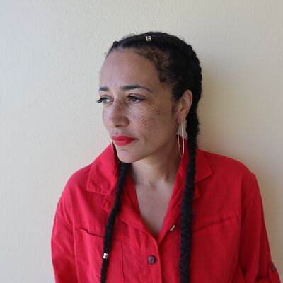 Author Zadie Smith wearing hoop earrings and a red shirt