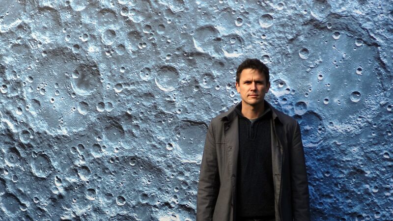 Artist Luke Jerram – a white man with short dark hair – stands in front of his work Museum of the Moon