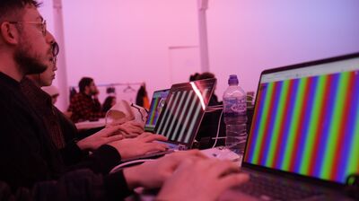 A series of laptops using the Hydra coding software in a purple lit room