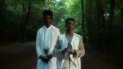 Two people dressed in white standing in a wood