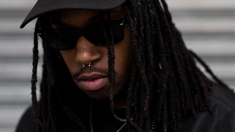 Artist Ivan Michael Blackstock wearing a black jacket, black baseball cap and sunglasses.