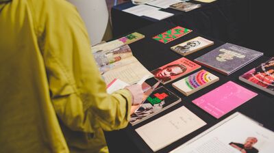 A person in a lime green shirt browsing a selection of poetry books