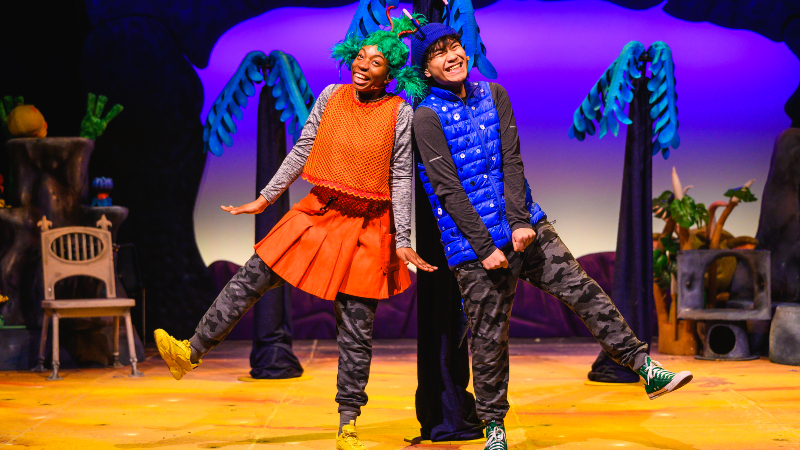 Two performers dressed as aliens stand next to each other