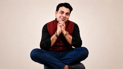 Amit Tandon sitting cross-legged wearing a red shirt