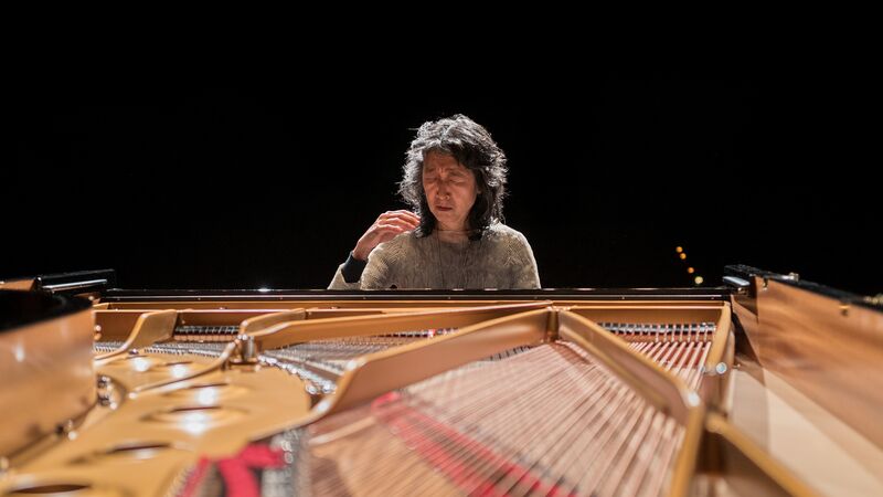 Mitsuko Uchida playing the piano, with their eyes closed.