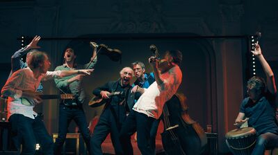 A musical group, standing in random poses on stage