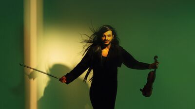 Violinist Nemanja Radulović in a dark outfit on a green background
