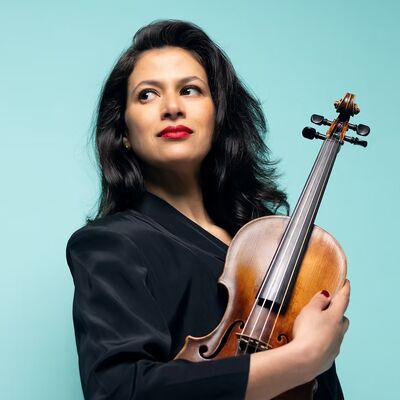 Elena Urioste standing holding a violin.