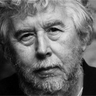 A black and white portrait of an older man with gray hair and a beard looking at the camera.