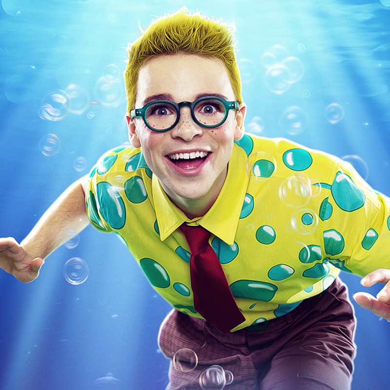 A boy wearing a yellow shirt with bubbles on underwater