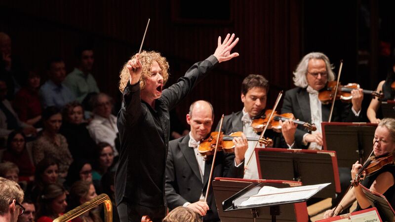 Santtu-Matias Rouvali conducts Mahler at the Royal Festival Hall, the image shows four violinists and Santtu conducting with a section of the audience shown in the background