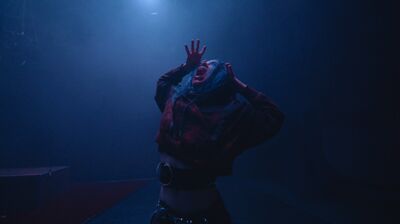 A woman is screaming in the dark, it looks as though she is under water with a small crack of light shining through the top of the image