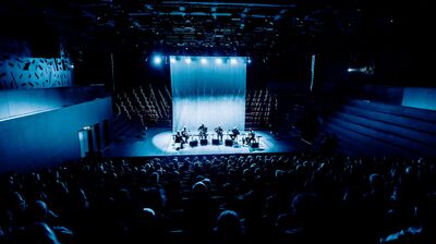 Musicians playing large drums on stage under bright white lights