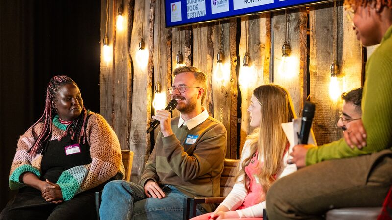Next Verse: A Young Poets' Summit image shows five people talking on a panel with a warmly lit wooden background