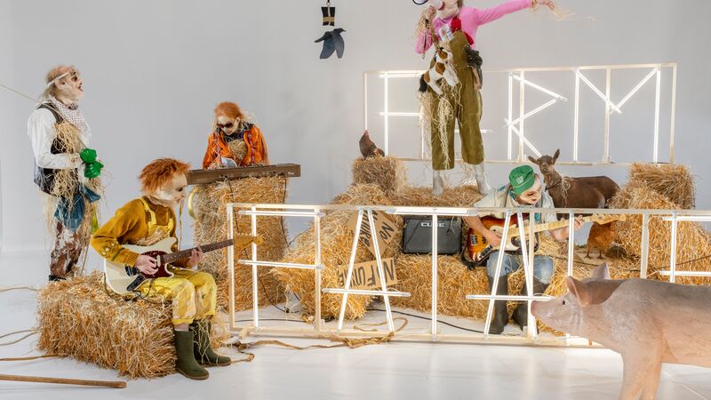 Five scarecrows sit on hay bails playing different instruments