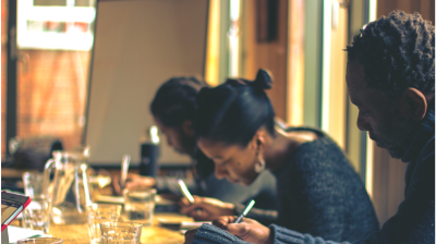 Three people sitting toegther, focused and writing separately