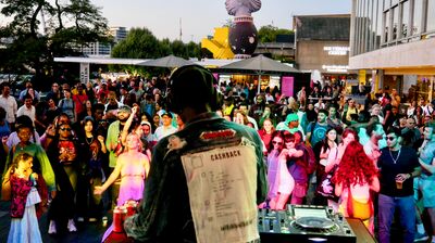 A man dj'ing in front of crowd on the Riverside Terrace